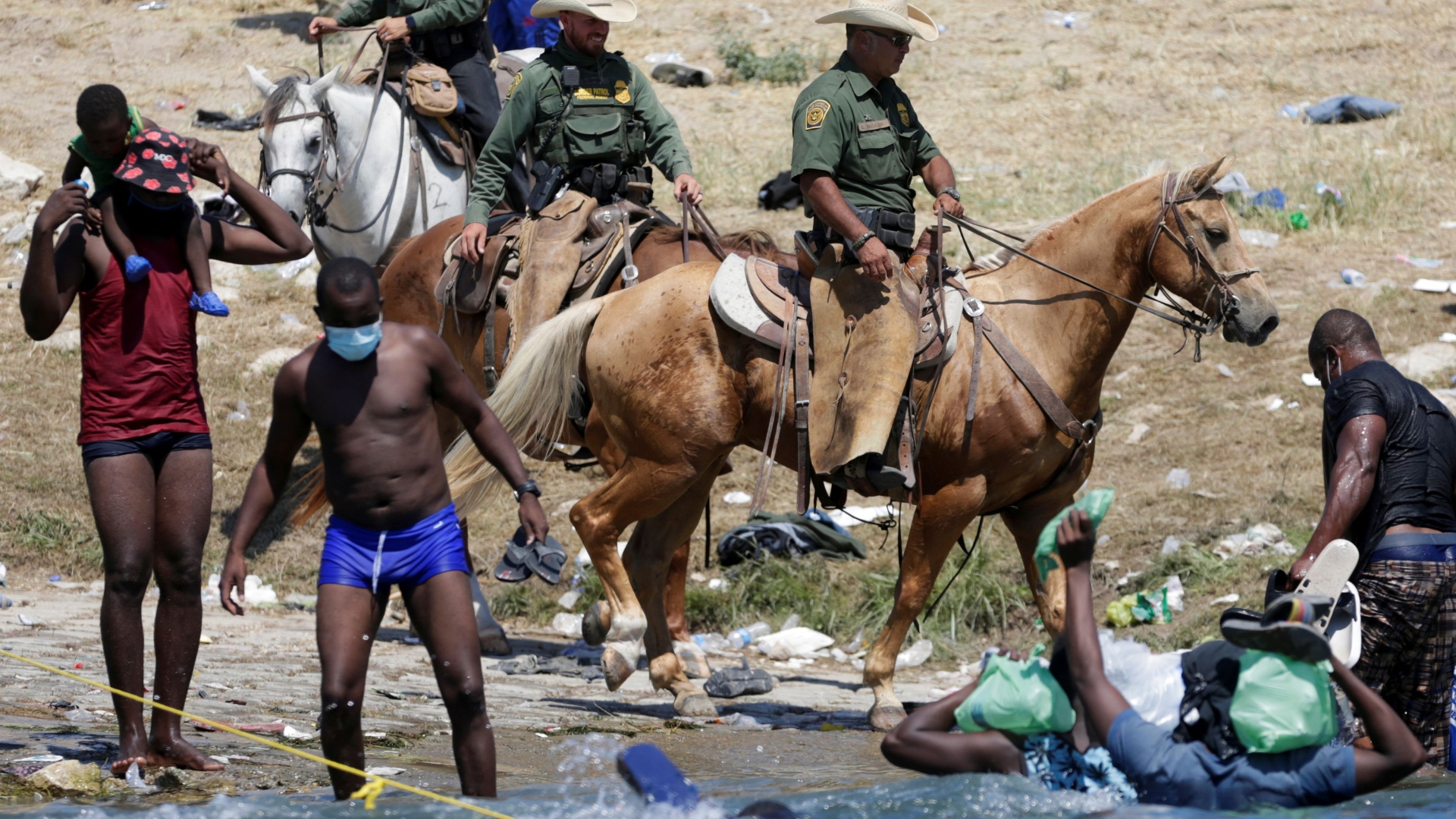 U.S. border officials on horseback try to stop migrants crossing from Mexico